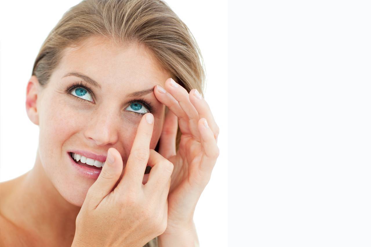 Woman blonde putting in contact lens